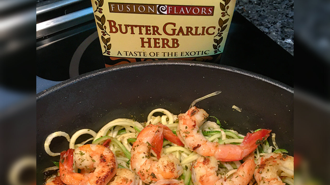 Skillet with zucchini noodles as the base with several shrimps on top with scampi sauce made from butter garlic herb seasoning made by Kitchen Fusions.