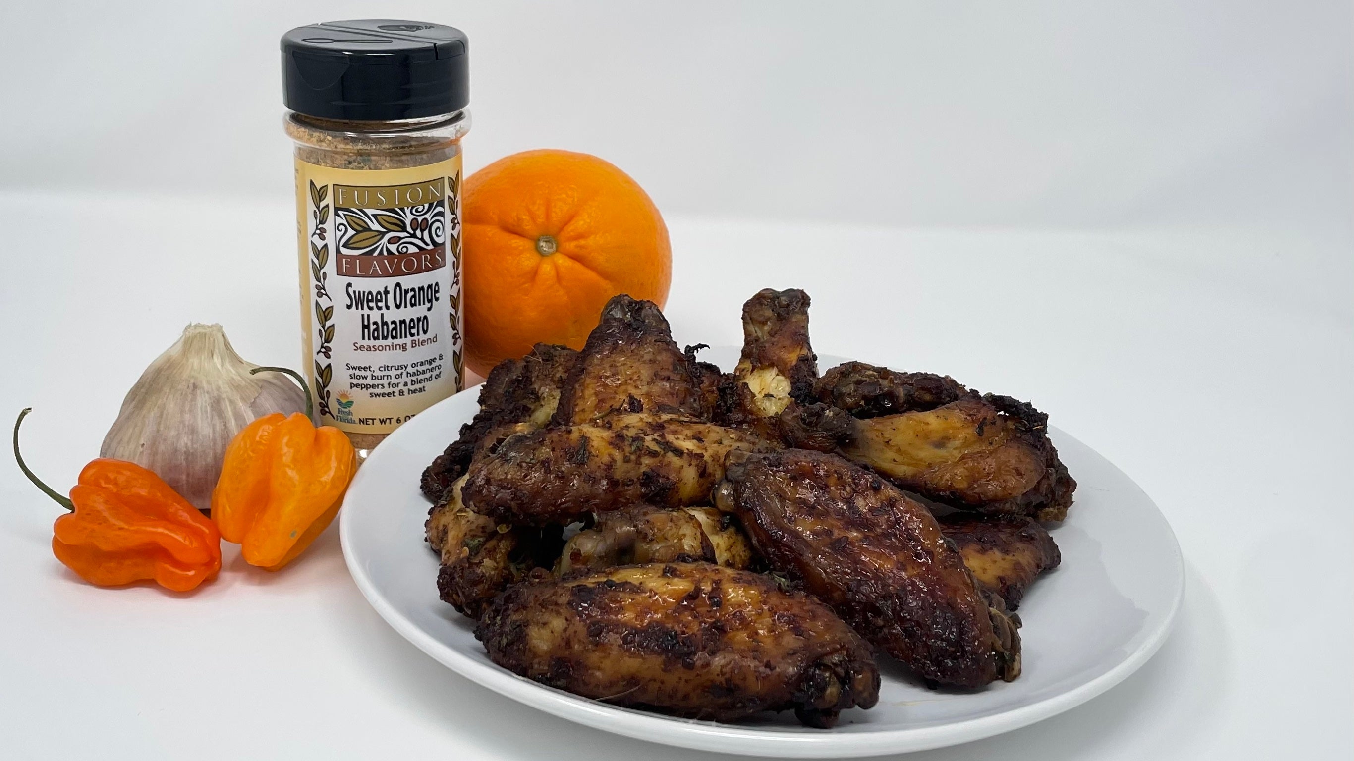 Plate of chicken wings with a sweet orange habanero seasoning blend bottle. 