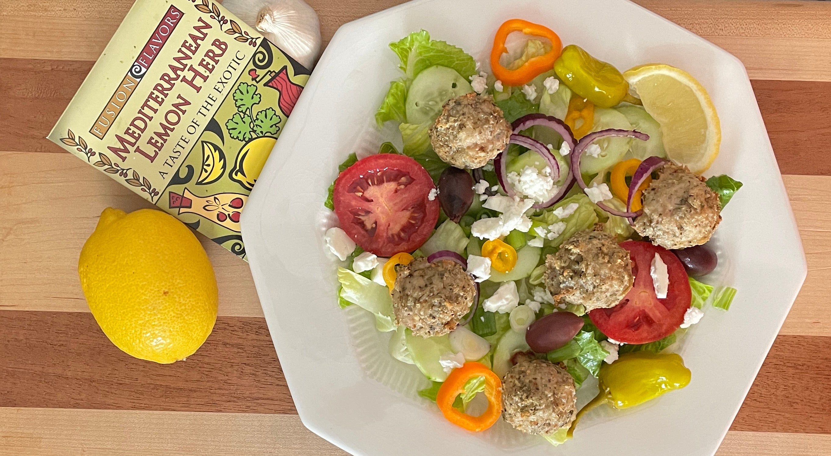 Mediterranean Meatballs seasoned with Fusion Flavors Greek Seasoning blend plated on a greek salad