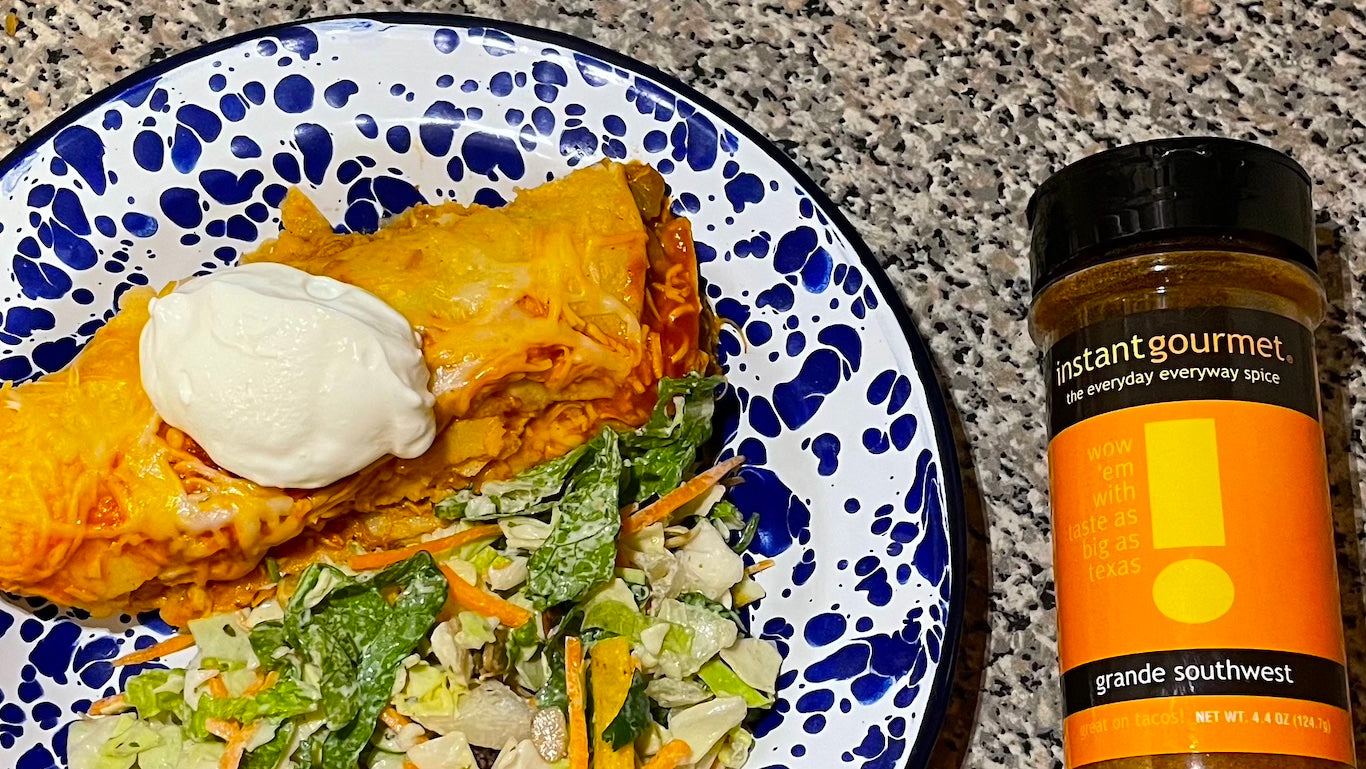 Enchiladas and southwestern salad shown on blue and white plate garnished with sourcream, also show Instant Gourmet seasoning blend bottle.