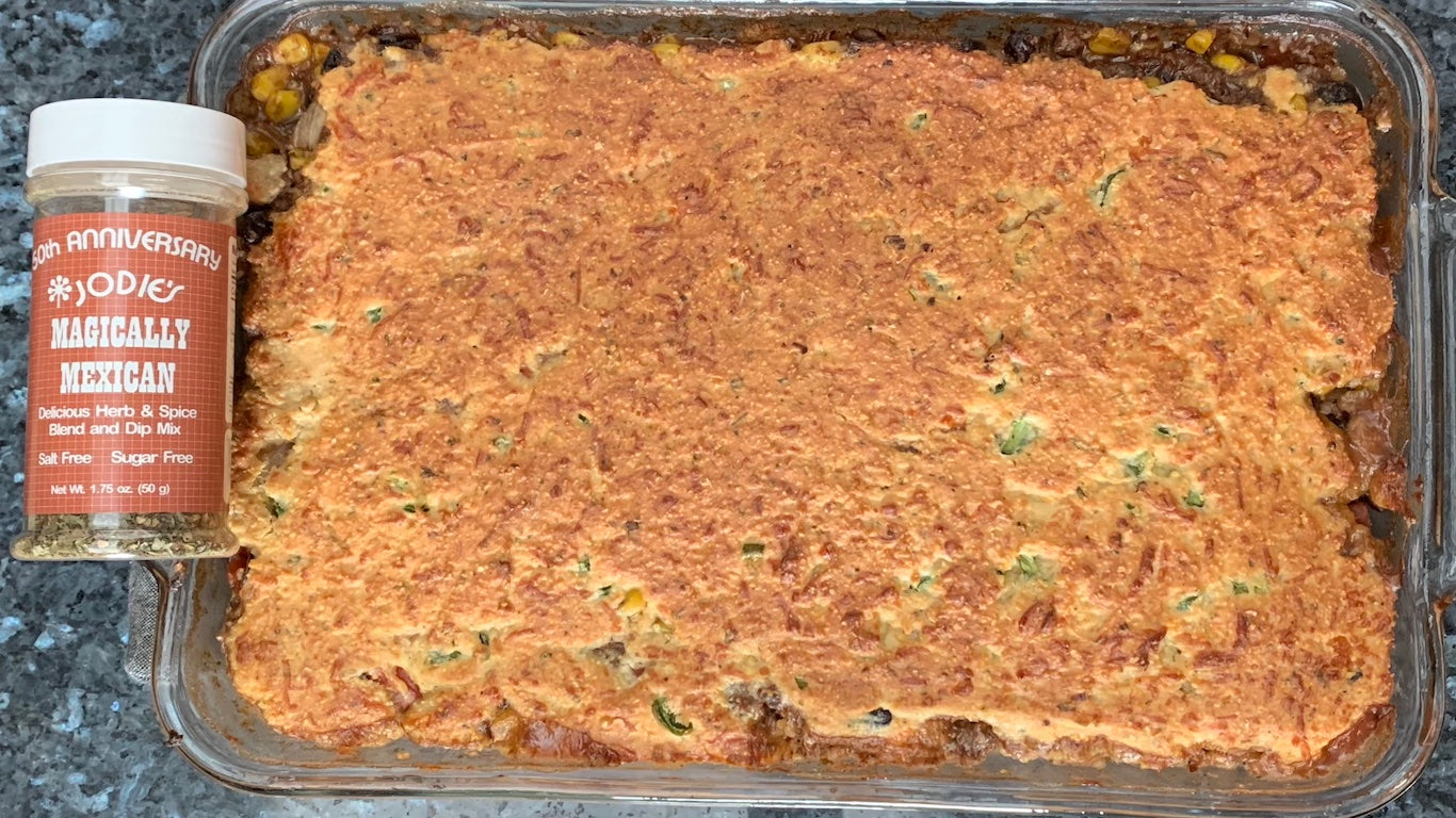 Casserole dish with the Tamale pie freshly baked. Also a bottle of Jodies Kitchen Magically Mexican seasoning blend next to the casserole. 